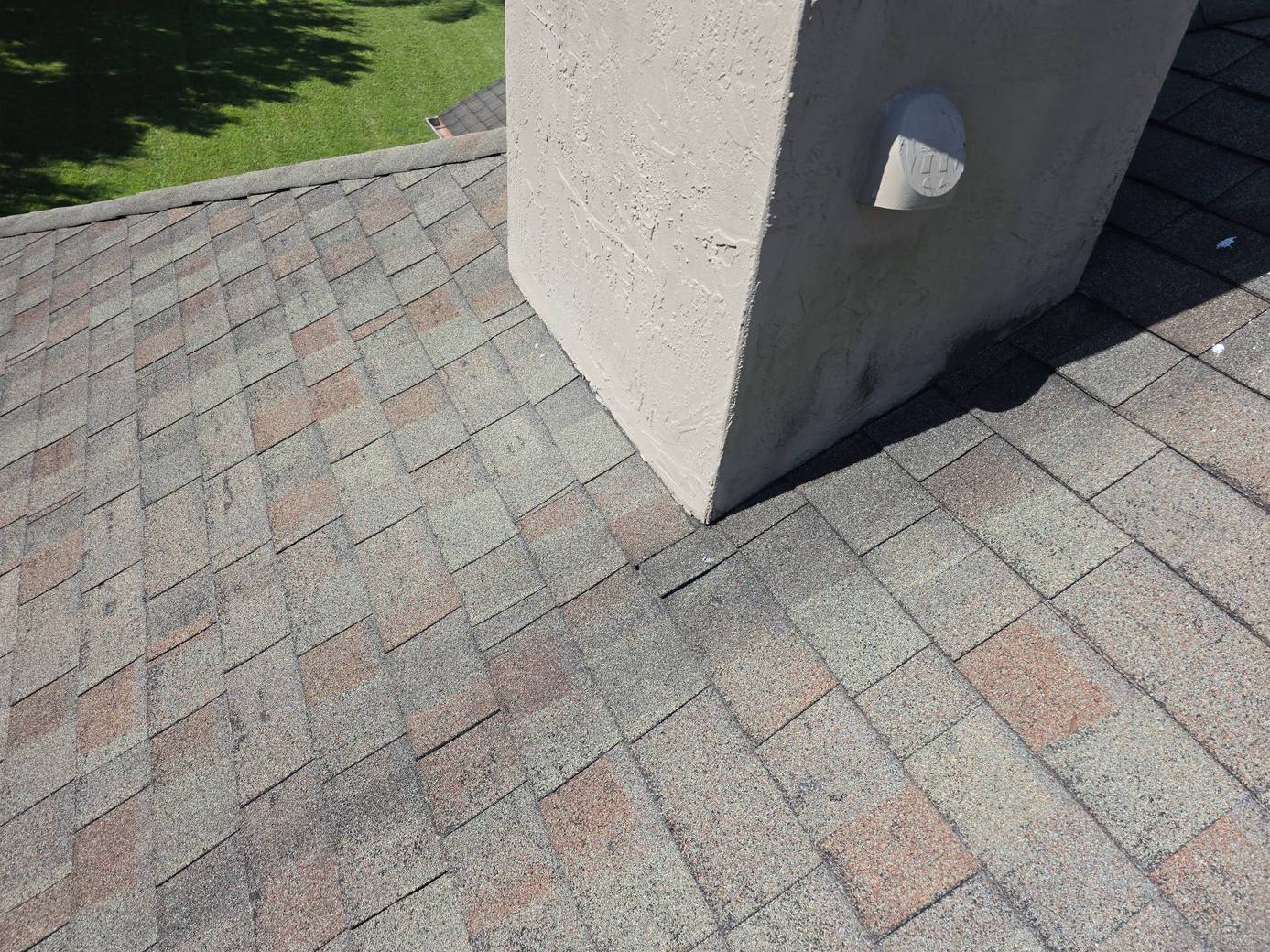 Worn old shingles next to the stucco chimney on a Deltona FL roof