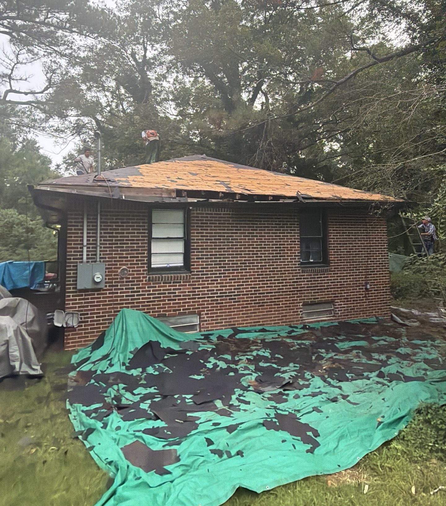 Old shingles torn off onto tarps beside a brick home in Atlanta GA